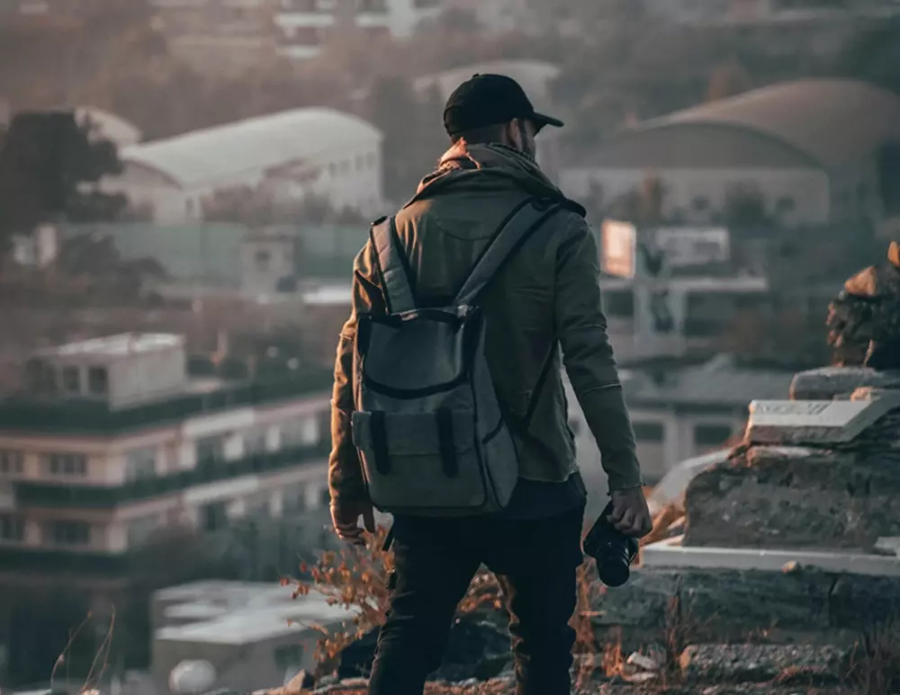 Photographer with a DSLR camera standing on an urban rooftop, capturing the sunset over the city